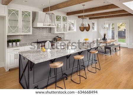 Beautiful Kitchen in New Luxury Home with Large Island, Hardwood Floors, Range Hood, and Glass Fronted Cabinets, Horizontal Orientation; Lights are off Royalty-Free Stock Photo #634668494