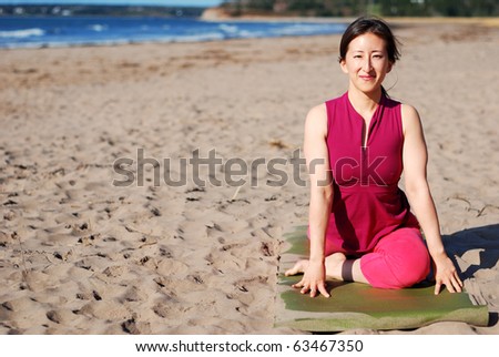 A young woman practices yoga on the beach.