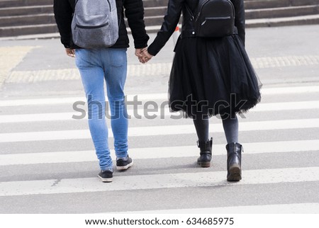 Back view of girlfriend and boyfriend cross the road on zebra
