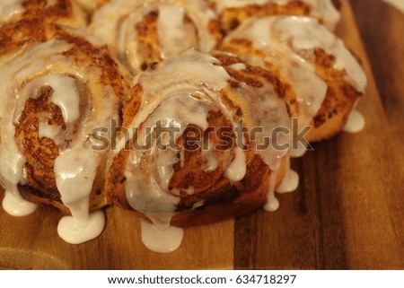 Closeup on a bunch of cinnamon buns with perfect sugary icing. Dessert on a wood plate.