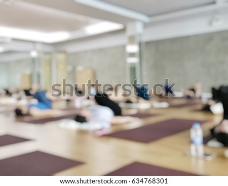 Blurred abstract background sporty healthy peoples playing yoga on mat with relaxing back position in Vinyasa studio classroom.  Blurry view strong strength athlete women in yoga fitness wellness gym.