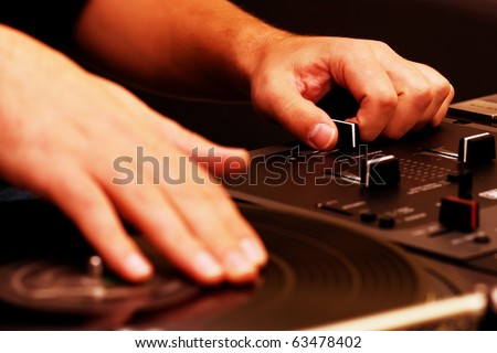 Hip hop dj scratches vinyl record on turntable. Hands of disk jockey mixing tracks on party in night club. Disc jokey using crossfader knob on sound mixer to remix musical track with turntable scratch