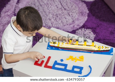 Ramadan Kareem with a ship, a child making  (Ramadan Kareem ) words in bricks  , translations: arabic language which means ''Ramadan kareem'' (a month of fasting in Islam).