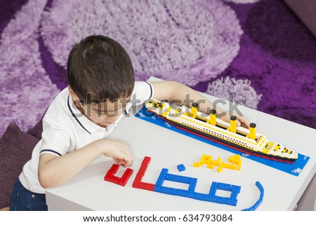 Ramadan Kareem with a ship, a child making  (Ramadan Kareem ) words in bricks  , translations: arabic language which means ''Ramadan kareem'' (a month of fasting in Islam).