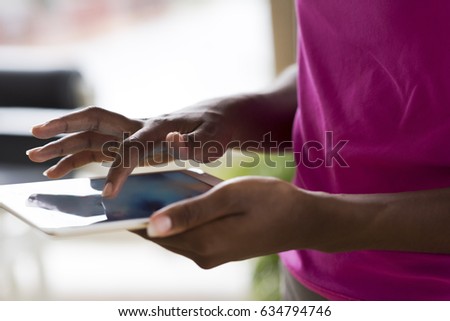 beautiful african american woman using tablet computer from home while rain and bad weather is outdoor