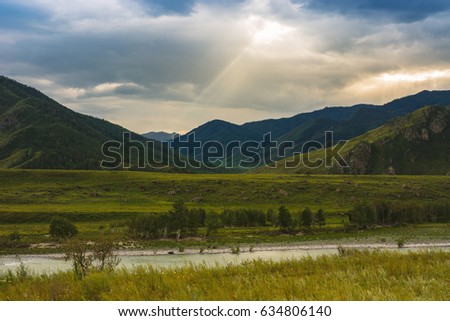 The ray of the sun makes its way through the clouds. Mountains and hills. The Katun River.