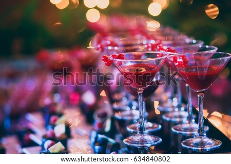 Beautiful row line of different colored alcohol cocktails on a party, martini, vodka,and others on decorated catering bouquet table on open air event, picture with beautiful bokeh
