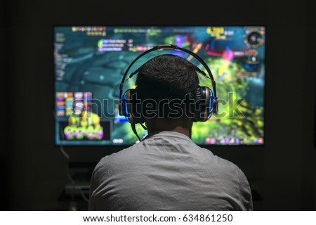 Young gamer playing video game wearing headphone. Royalty-Free Stock Photo #634861250