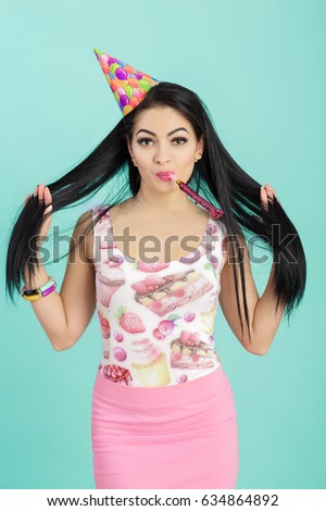 portrait of funny woman in birthday hat and pink shirt on the blue background. Celebration and party. Having fun.