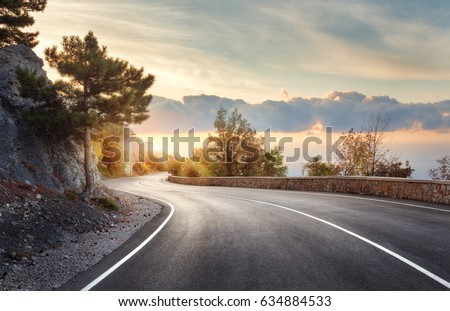 Asphalt road. Landscape with rocks, sunny sky with clouds and beautiful mountain road with a perfect asphalt at sunrise in summer. Vintage toning. Travel background. Highway in european mountains