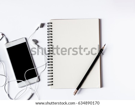 Smart phone with headphones and blank notebook with pencil and copy space on white background,flat lay concept.