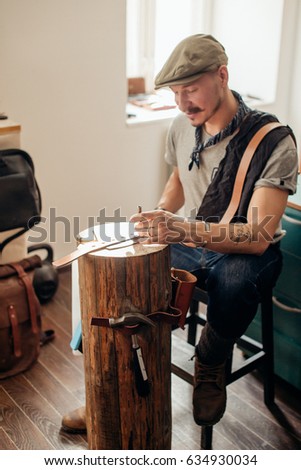 caucasian leather craft mustache man wearing cup working as artisan in his workshop
