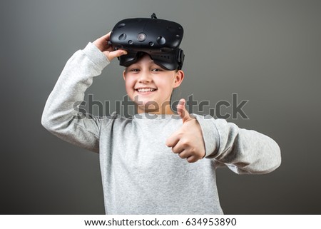 Happy little girl using a virtual reality headset show thumbs up