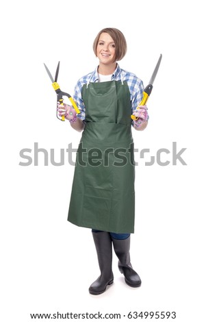 full length portrait of smiling woman professional gardener or florist in apron holding grass shears and pruning saw isolated on white background. gardening service, garden design and business concept