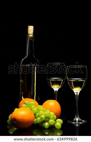 Three glasses for wine, a bunch of grapes and oranges on a black background, studio light