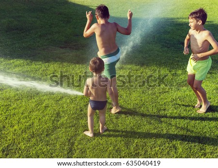 Happy summer vacation for kids on green meadow splash sprinkle water