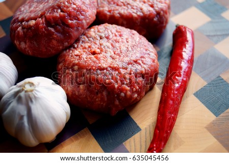 Meat burgers on wood board with red pepper and spices             