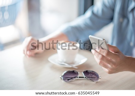 man hand texting message on social media application by phone, casual professional entrepreneur using smartphone in cafe or coffee shop, modern lifestyle and digital age concepts