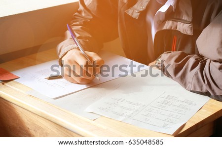 boy student testing in exercise paper, exams answer sheets on wood table in classroom Royalty-Free Stock Photo #635048585