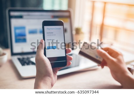 Man hands using smartphone and laptop computer for online shopping at home, Hand holding mobile phone with Payment Detail page display and credit card, online shopping concepts Royalty-Free Stock Photo #635097344