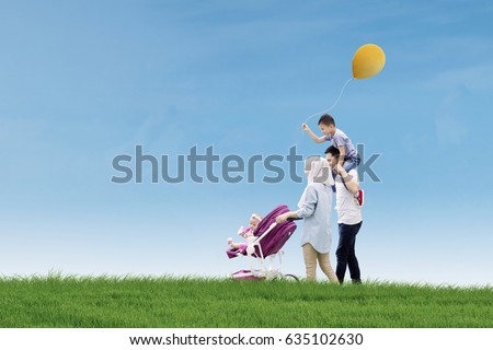 Picture of happy parents spending time with their children while walking together in the meadow