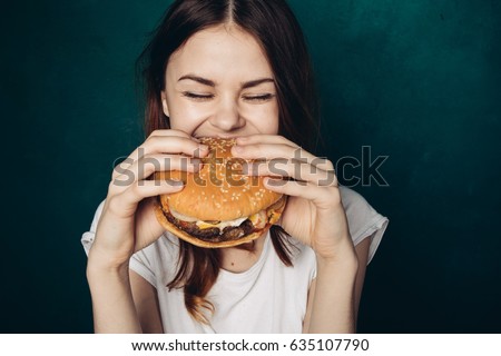 A woman eats with great pleasure, a woman eats a burger, food Royalty-Free Stock Photo #635107790
