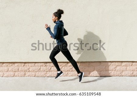 Side view of female athlete running against wall Royalty-Free Stock Photo #635109548