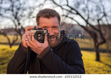 A mature man  takes pictures on a mirrorless camera in the street. Hobby of photography. New trends in photographic technique.