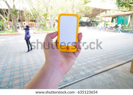 Girl using smart phone at the outdoor park. hand holding smart phone with blank and white screen. Colorful smart phone with vintage tone. hand holding using mobile phone in the public place.
