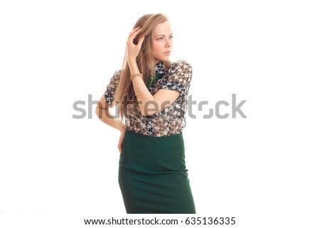 beautiful young girl in green skirt and blouse keeps an arm near hair and looks toward