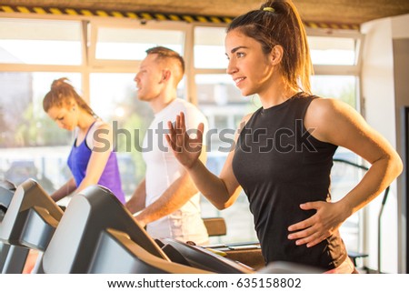 Young sporty woman running on a treadmill at gym.