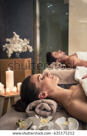 Young man and woman lying down on massage beds at Asian luxury spa and wellness center Royalty-Free Stock Photo #635175212