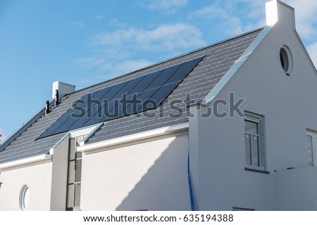 Newly build houses with solar panels attached on the roof against a sunny sky Close up of new building black solar panels.( Zonnepanelen ) translation:  Solar  panel, Zonne energie, Sun Energy