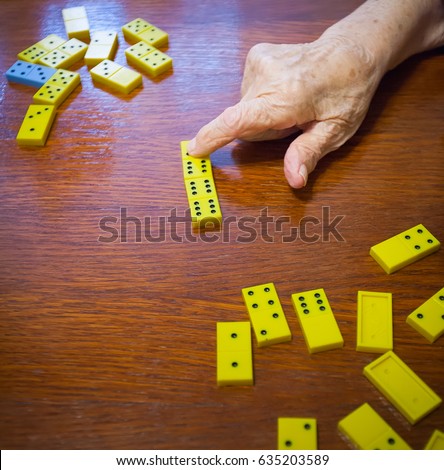 Board game dominoes. Grandmother points with a finger at the yellow domino.