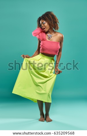 Fashion photo of young african girl posing over green background in studio