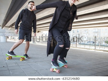 Girl and a guy on a skateboard ride under a bridge, a geometric perspective in a photo