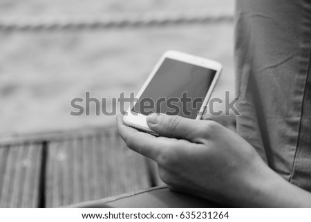 Closeup on person using mobile smartphone over sandy beach background. Photography concept for online connection, communication messaging, banking..