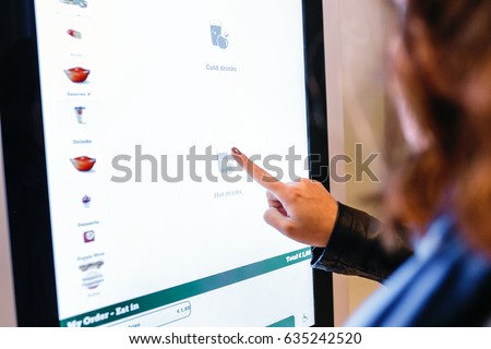 A woman orders food in the touch screen terminal in the electronic menu in the restaurant Royalty-Free Stock Photo #635242520