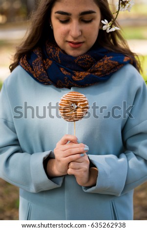 Young girl in blue coat with fresh donuts and coffee. Outdoors lifestyle spring portrait