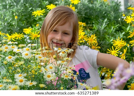 little girl seven years old, surrounded by daisy flowers in a botanical garden, eyes open, looking at camera, cheerful and smiling, long blond, wheat hair, happy baby, sunny, bright day, arm at waist