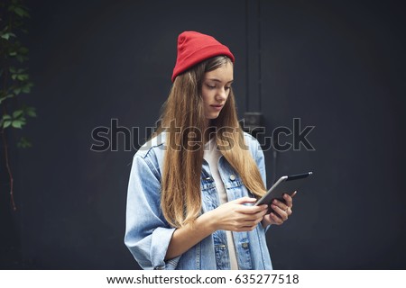 Young hipster girl installing new application for photo editor for creating cool pictures for improving own blog on internet websites on modern digital tablet standing outdoors in wifi zone