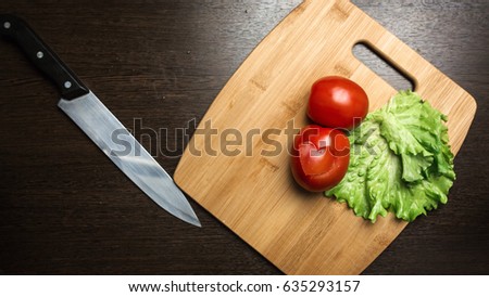 tomato and a kitchen knife on a cutting board