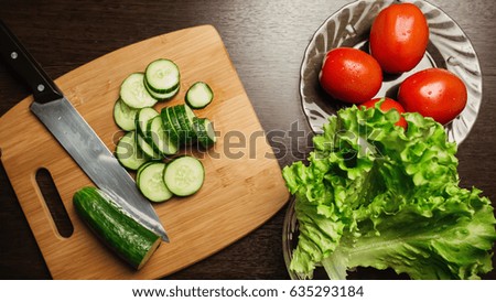 slices of cucumber, tomato and a kitchen knife on a cutting board