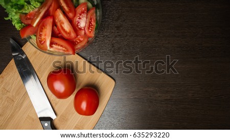 tomato and cut tomato, cucumber and a kitchen knife on a cutting board