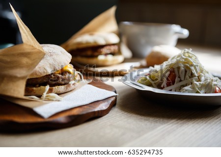 Traditional Serbian dish Pljeskavica.Fresh grilled burger with roasted beef meat,cheese slice,vegetables served in crusty bread bun.Food dish on table in fastfood restaurant.Royalty free image