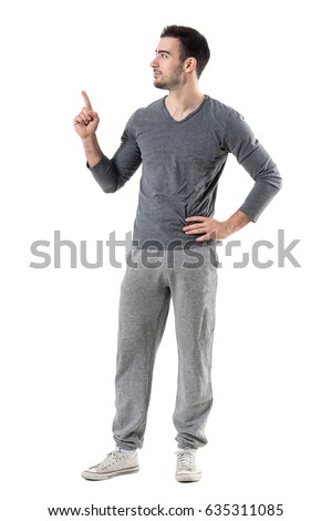 Fit sport man in sweat pants and gray shirt pointing finger up looking at copyspace. Full body length portrait isolated on white studio background.  Royalty-Free Stock Photo #635311085