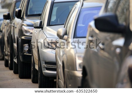 Many parked in a row of cars.