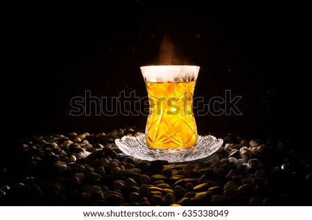 Turkish Azerbaijan tea in traditional glasse and pot on black background with lights and smoke. Eastern tea concept. Armudu traditional cup
