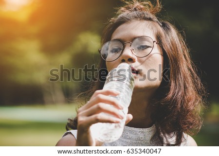 closeup images of young beautiful dark brown haired woman drinking water at summer green park Royalty-Free Stock Photo #635340047