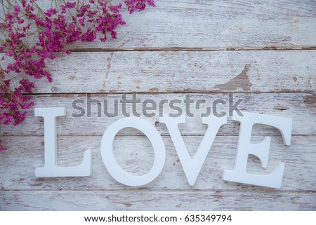 LOVE white character on old wooden background with dry flowers around